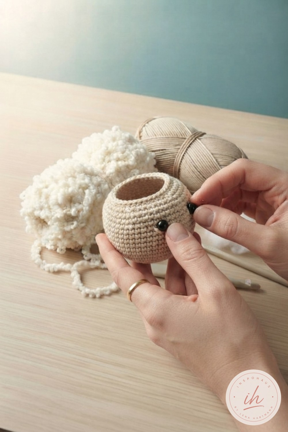 Sicherheitsaugen werden in den gehäkelten Kopf für das Lamm Amigurumi eingesetzt, Stopföffnung oben noch sichtbar
