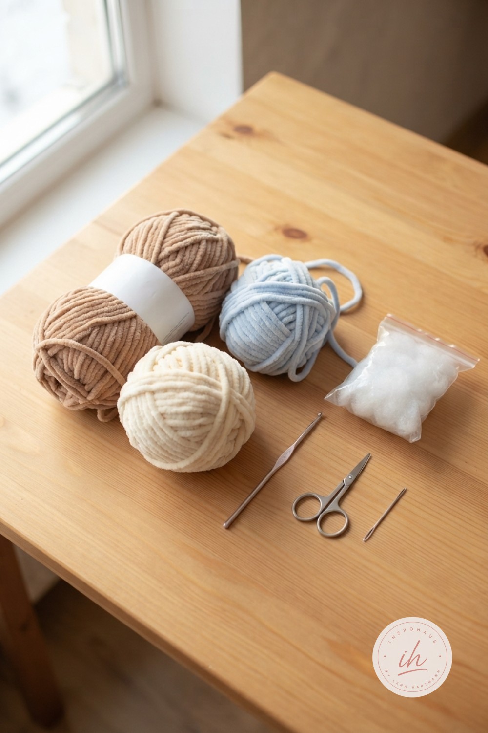 Otter Fisch Amigurumi häkeln beginnt mit Chenillegarn in Braun, Creme und Hellblau samt Häkelnadel und Sicherheitsaugen auf Holztisch