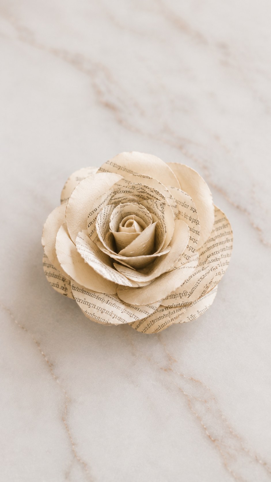 Fertige Papierrose aus Buchseiten liegt auf Marmoruntergrund und zeigt die feine Textur des Papiers