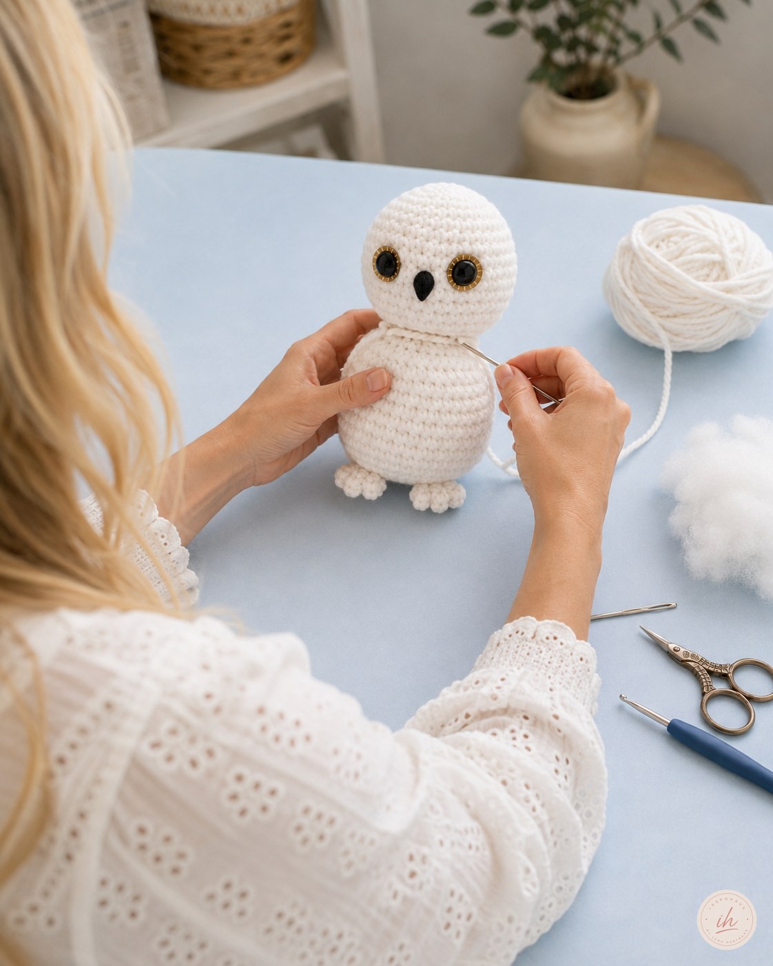 Kopf und Körper der Schneeeule werden am Tisch mit der Wollnadel zusammengenäht