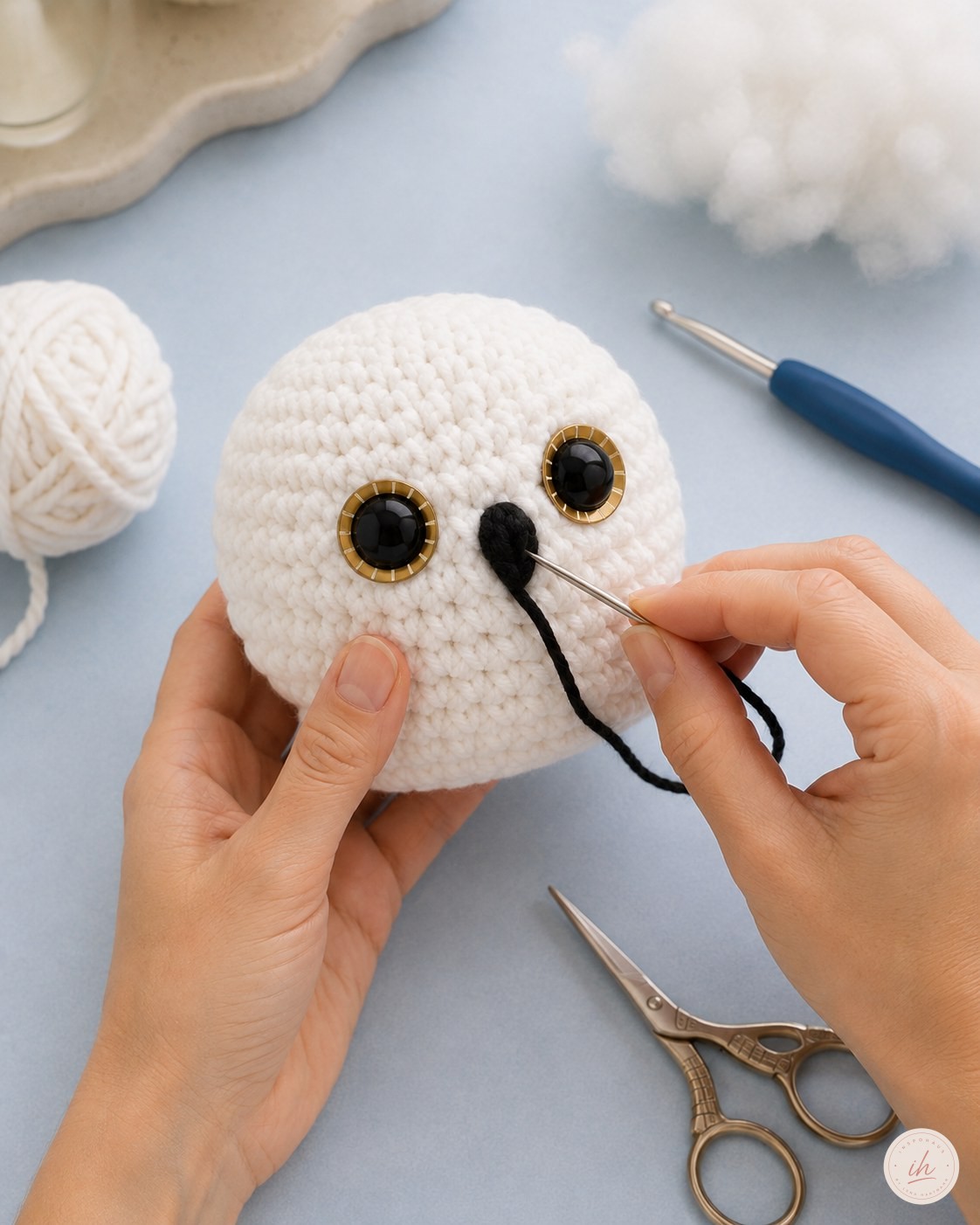 Sticken des schwarzen Schnabels auf dem Kopf der Schneeeule Amigurumi mit der Wollnadel