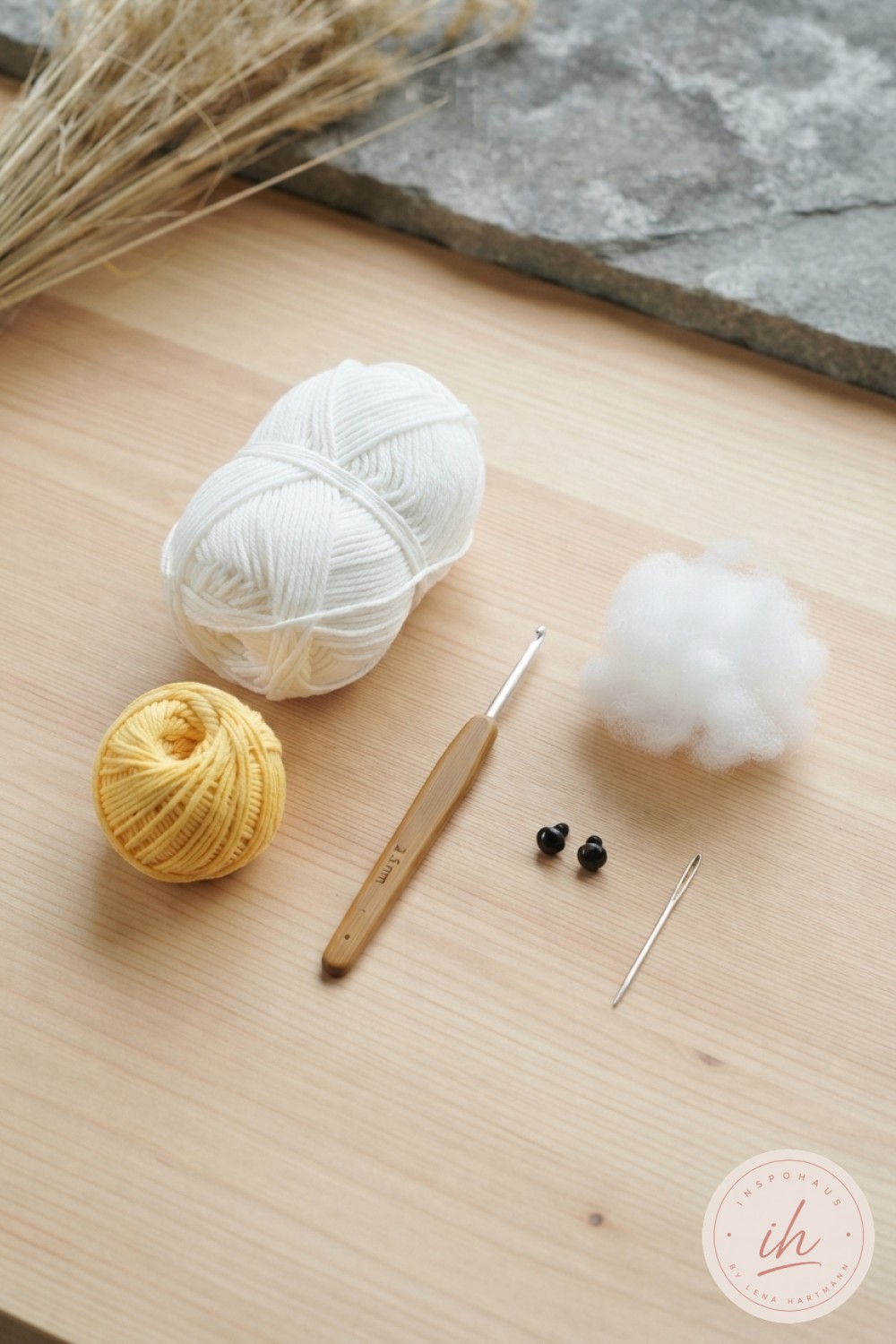 Material für weiße Ente Amigurumi häkeln: Baumwollgarn, Häkelnadel, Sicherheitsaugen und Füllwatte auf Holztisch
